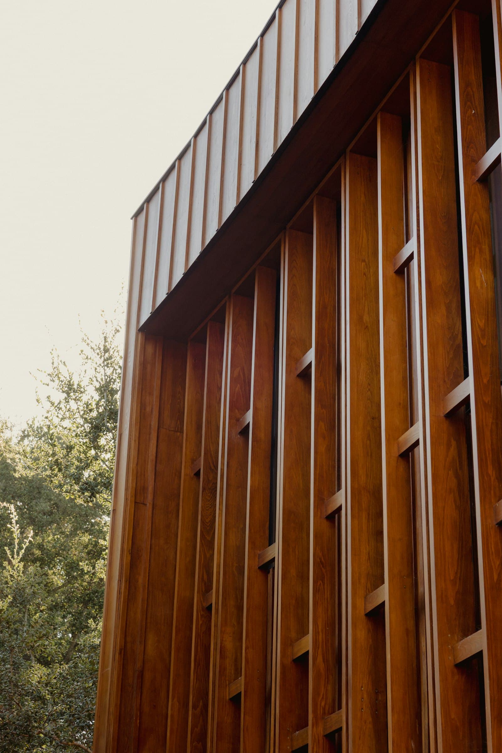 A modern building facade clad in vertical warm-toned timber slats